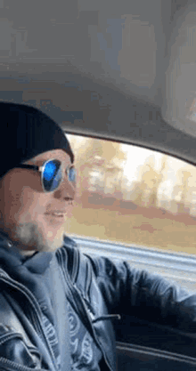 a man wearing sunglasses is driving a car .