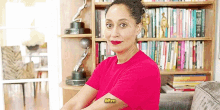 a woman in a pink shirt is sitting on a couch in front of a bookshelf in a living room .