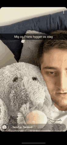 a snapchat of a man laying in bed with a stuffed animal