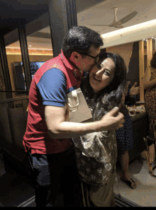 a man kisses a woman on the cheek while holding a gift