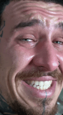 a man with a tattoo on his forehead is smiling and making a funny face