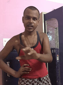 a man wearing a red tank top stands in front of a blue closet