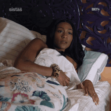 a woman laying on a bed with the word sistas above her head