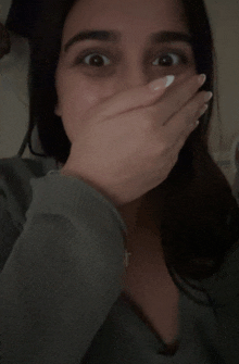 a woman is covering her mouth with her hand and looking surprised