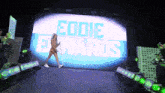 a woman is walking in front of a large screen that says eddie ewards