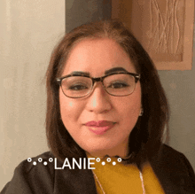 a woman wearing glasses and a yellow sweater has the word lanie written on her face