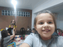 a girl in a gray shirt is smiling in front of a group of children