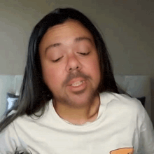 a man with long hair and a beard wearing a white shirt