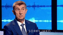 a man in a suit and tie is sitting in front of a microphone on a television show .