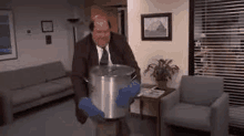 a man in a suit and tie is holding a large pot in his hands .