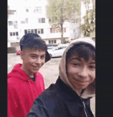 two boys are posing for a picture and one is wearing a hooded jacket