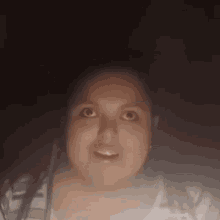 a woman is looking up at the camera in a dark room .