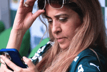 a woman wearing sunglasses looks at her phone