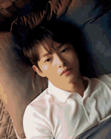 a young man in a white shirt is laying down on a bed