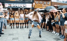 a group of women are dancing on a sidewalk in front of a restaurant with chinese writing on the front