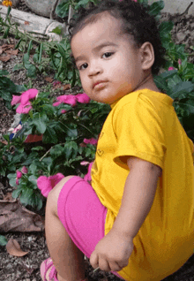 a little girl in a yellow shirt and pink shorts