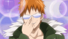 a man with orange hair is wearing sunglasses and covering his eyes with his hand .