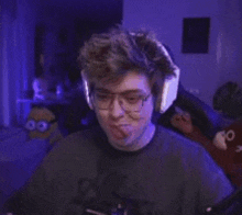 a man wearing headphones and glasses is sticking his tongue out in a dark room .