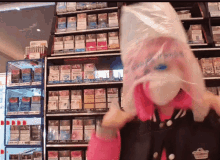 a woman in a pink jacket is holding a plastic bag over her head in front of a shelf of cigarettes