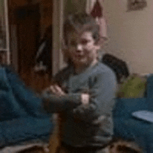 a young boy is sitting on a chair with his arms crossed in a living room .