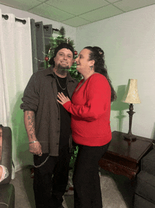 a man and a woman pose for a picture in front of a christmas tree