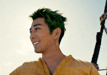 a man with green hair is smiling and wearing earrings