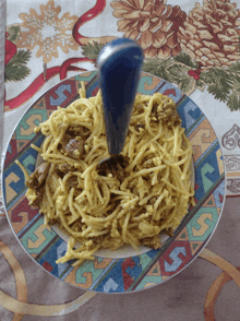 a plate of spaghetti with a blue spoon on top of it