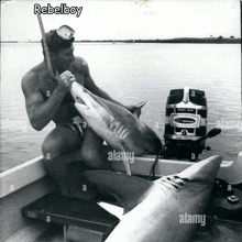 a man is holding a shark in a boat with a rebelboy logo above him