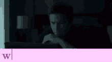 a man is sitting in the dark looking at a laptop computer .