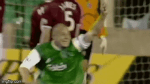 a soccer player in a green shirt is being tackled by another player in a red jersey .