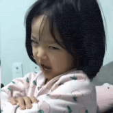 a little girl is sitting on a bed with her mouth open and making a funny face .