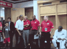 a group of men in red shirts are standing in a locker room with a sign that says ' one way '