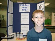 a boy stands in front of a sign that says bitches ain t shit