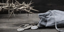 a crown of thorns and a bag of silver coins on a wooden table