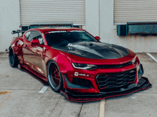 a red car with the word american authority on the windshield is parked in a parking lot