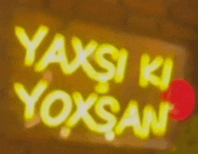 a yellow sign that says yaxsi ki yoxsan on a brown background