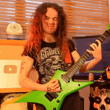 a man playing a green guitar in front of a youtube logo