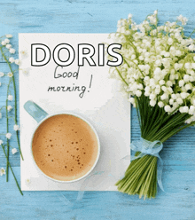 a bouquet of lily of the valley flowers sits next to a cup of coffee and a card that says doris good morning