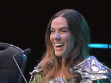 a woman is smiling in front of a microphone while wearing a silver armor