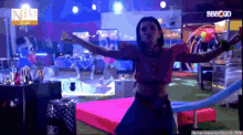 a woman in a pink top is dancing on a stage in front of a sign that says bb2020