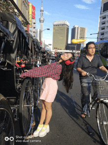 a girl wearing red headphones is leaning on a bicycle while a man rides behind her