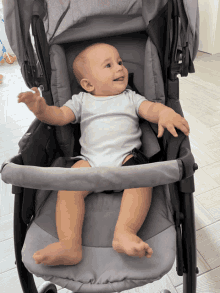 a baby is sitting in a stroller and smiling for the camera