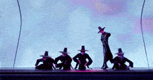 a group of people are standing in a row on a stage wearing hats .