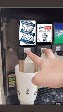 a cup of soda is being poured from a soda dispenser that says birmingham city football club