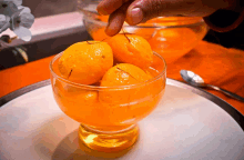 a glass filled with oranges and a spoon on a table