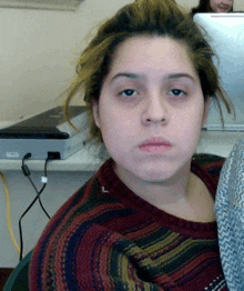 a woman in a striped sweater is sitting at a desk