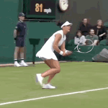 a woman in a white dress is holding a tennis racquet on a tennis court with a scoreboard that says 81 mph