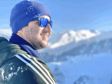 a man wearing sunglasses and a blue hat stands in the snow