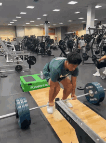 a man squatting down to lift a barbell in a gym with a green box in the background that says plyosoft bio