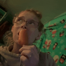 a girl with glasses is eating an orange